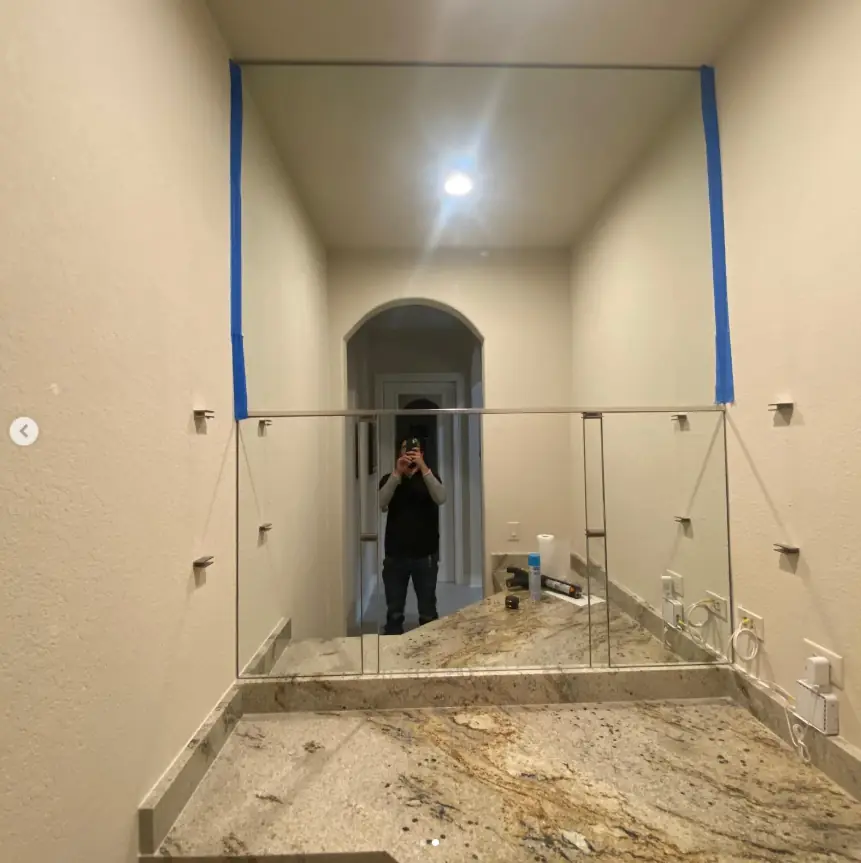 Frameless mirror wall over a stone vanity